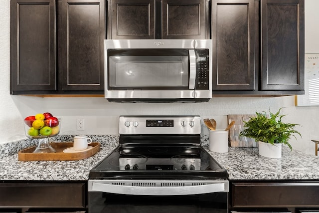 kitchen with light stone countertops, dark brown cabinetry, and appliances with stainless steel finishes