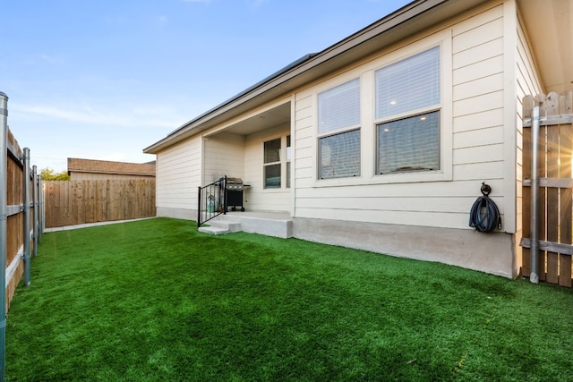 rear view of house featuring a fenced backyard and a lawn