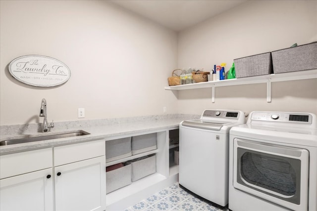 clothes washing area featuring sink, washer and dryer, and cabinets