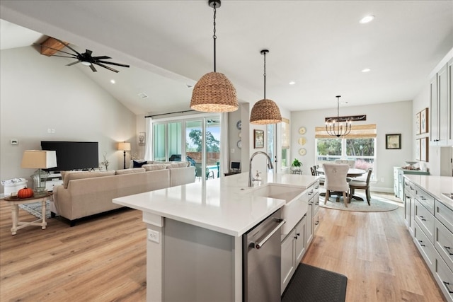 kitchen with an island with sink, pendant lighting, light hardwood / wood-style floors, lofted ceiling with beams, and sink