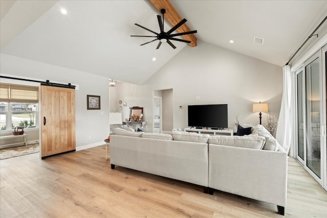 living room with beam ceiling, ceiling fan, a barn door, high vaulted ceiling, and light hardwood / wood-style flooring