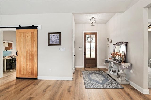 entryway with an inviting chandelier, a barn door, and hardwood / wood-style floors