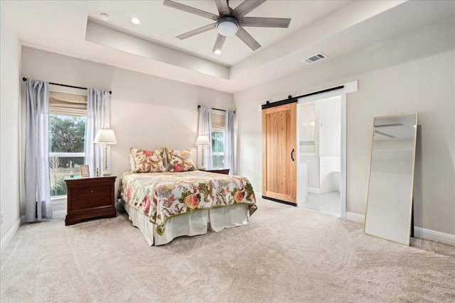 bedroom featuring light colored carpet, ceiling fan, and a barn door