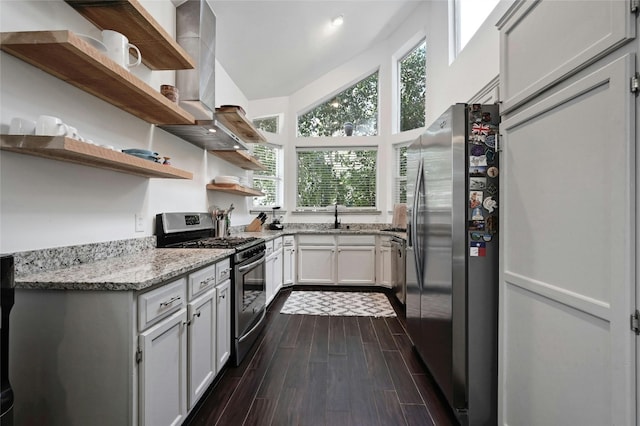 kitchen with lofted ceiling, wall chimney range hood, light stone countertops, dark hardwood / wood-style flooring, and stainless steel appliances