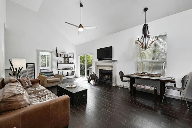 living room featuring a premium fireplace, high vaulted ceiling, ceiling fan with notable chandelier, and dark hardwood / wood-style floors