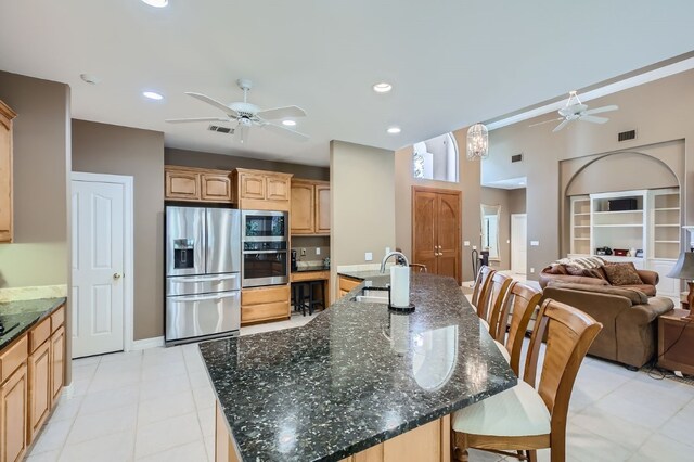 kitchen featuring a large island with sink, sink, stainless steel appliances, and ceiling fan