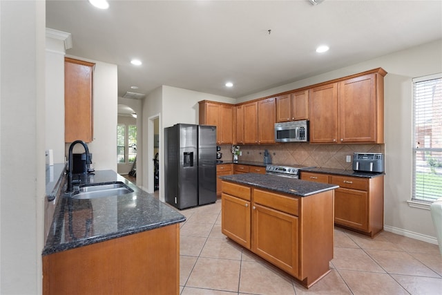 kitchen featuring sink, a kitchen island, dark stone counters, and appliances with stainless steel finishes