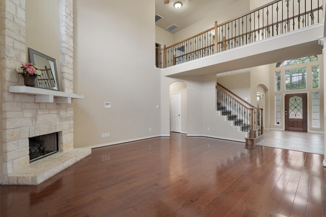 unfurnished living room with a towering ceiling, wood-type flooring, and a fireplace