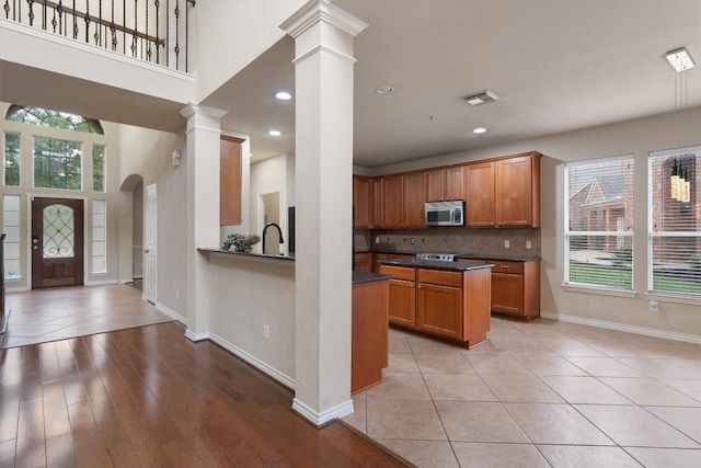 kitchen with light tile patterned floors, decorative columns, decorative backsplash, and a wealth of natural light