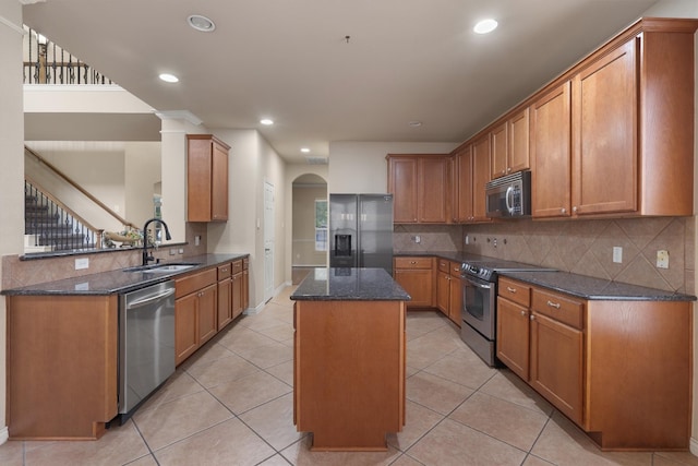 kitchen with sink, a center island, light tile patterned floors, dark stone countertops, and appliances with stainless steel finishes