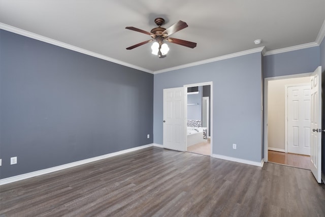 unfurnished bedroom featuring ensuite bath, ceiling fan, dark hardwood / wood-style floors, ornamental molding, and a walk in closet