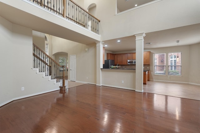 unfurnished living room with wood-type flooring and a high ceiling