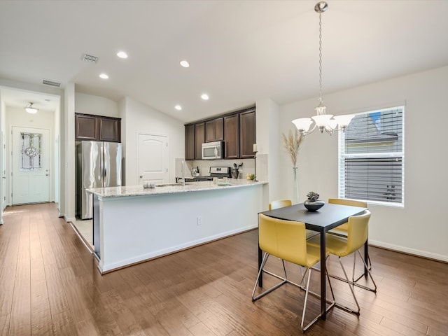 kitchen featuring hardwood / wood-style floors, hanging light fixtures, stainless steel appliances, and dark brown cabinets