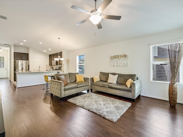 living room with vaulted ceiling, ceiling fan with notable chandelier, and dark hardwood / wood-style flooring