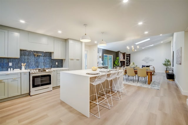 kitchen featuring a center island, hanging light fixtures, stainless steel stove, and light hardwood / wood-style floors