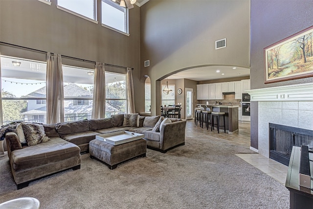 carpeted living room with a fireplace and a high ceiling