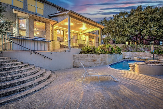 pool at dusk featuring a patio area