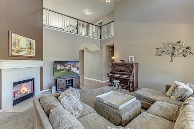 living area featuring baseboards, a high ceiling, and a fireplace