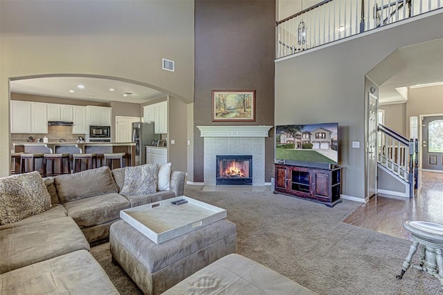 living room featuring visible vents, baseboards, a fireplace, stairs, and carpet flooring