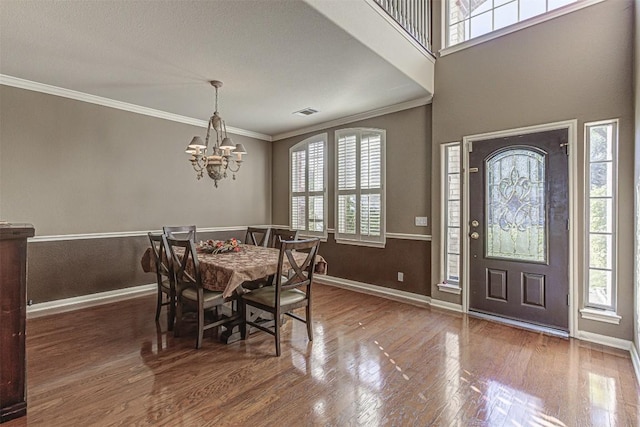 dining area featuring crown molding, wood finished floors, baseboards, and a chandelier