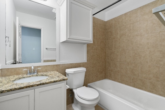 full bathroom featuring vanity, tiled shower / bath combo, toilet, and tile walls