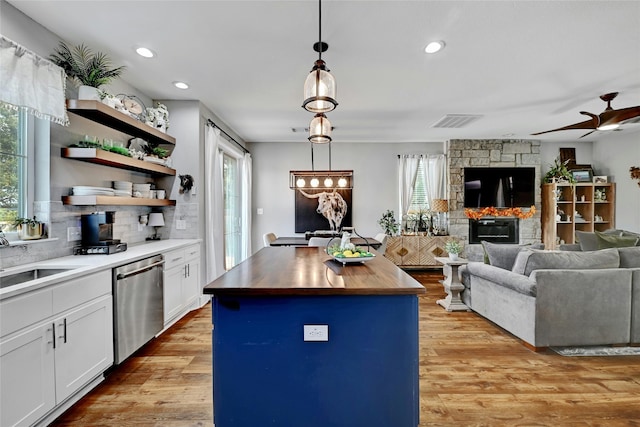 kitchen featuring dishwasher, a kitchen island, wood counters, pendant lighting, and white cabinets