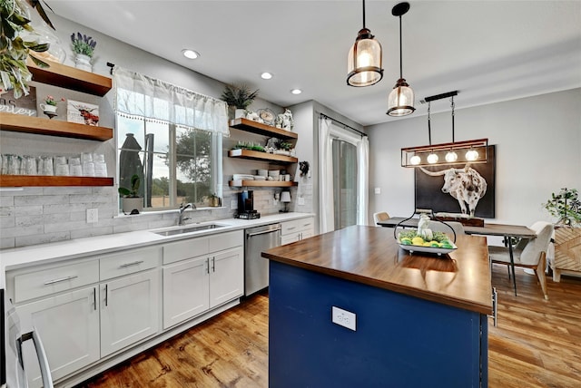 kitchen featuring dishwasher, a center island, white cabinets, sink, and butcher block countertops