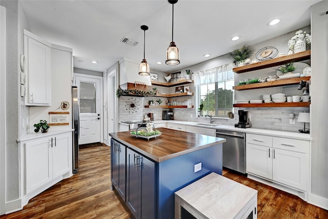 kitchen with decorative backsplash, dark hardwood / wood-style flooring, stainless steel appliances, white cabinets, and a kitchen island