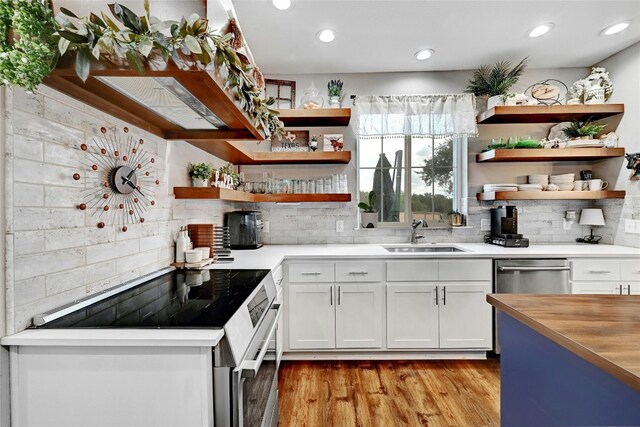 kitchen featuring range with electric cooktop, dishwasher, sink, backsplash, and white cabinets