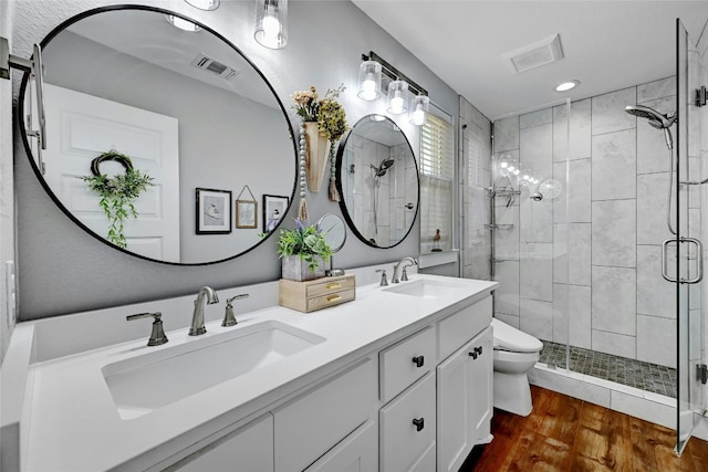 bathroom with vanity, wood-type flooring, a shower with shower door, and toilet