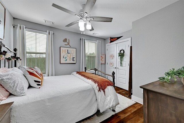 bedroom featuring ceiling fan, a closet, dark hardwood / wood-style flooring, and multiple windows