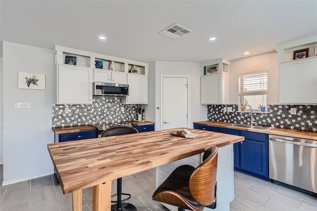 kitchen featuring wooden counters, white cabinets, stainless steel appliances, and blue cabinets