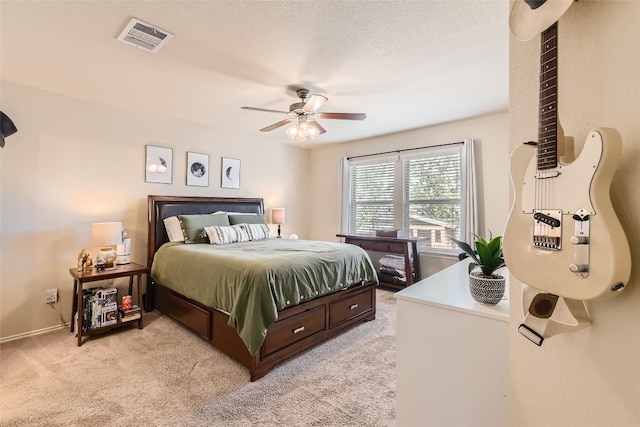 bedroom featuring a textured ceiling, ceiling fan, and light carpet