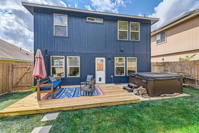 back of property with a lawn, a deck, and a hot tub