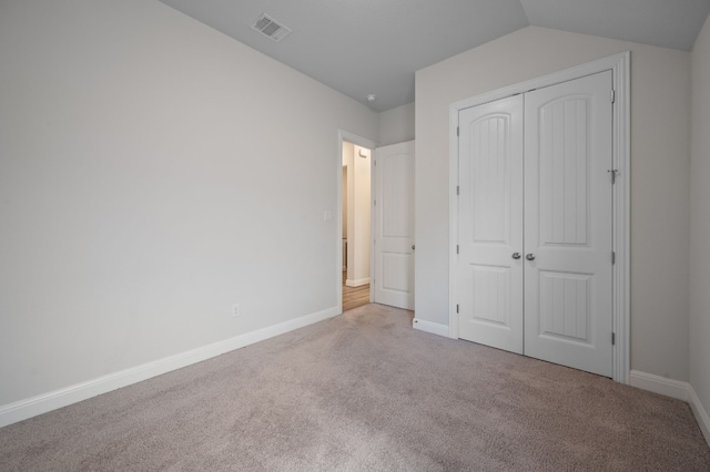 unfurnished bedroom with light carpet, a closet, and vaulted ceiling