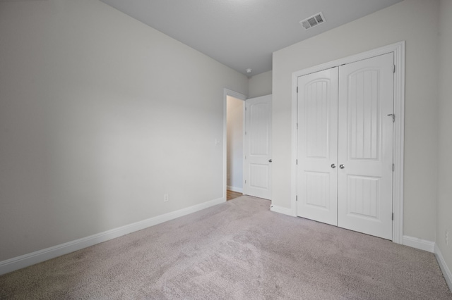 unfurnished bedroom featuring a closet and light colored carpet