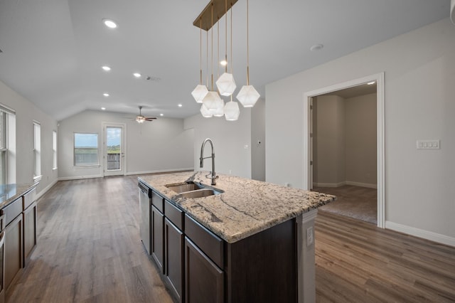 kitchen featuring dark wood-type flooring, hanging light fixtures, a center island with sink, sink, and vaulted ceiling