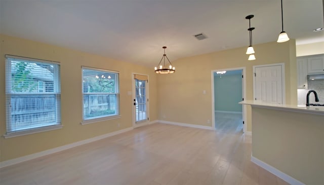 interior space featuring a notable chandelier, sink, hanging light fixtures, and light hardwood / wood-style flooring