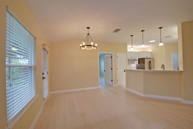 interior space featuring lofted ceiling, light wood-type flooring, and a chandelier