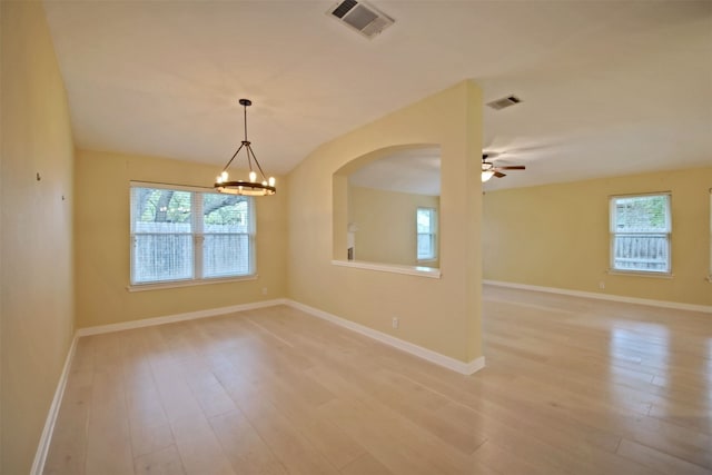 empty room with ceiling fan with notable chandelier and light wood-type flooring