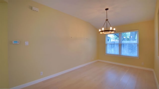 spare room featuring hardwood / wood-style flooring, vaulted ceiling, and an inviting chandelier