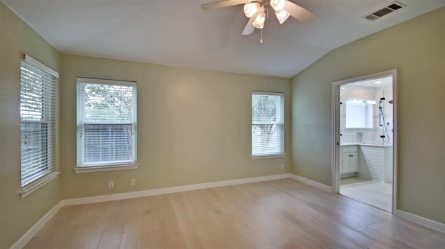 unfurnished bedroom featuring connected bathroom, light hardwood / wood-style floors, and multiple windows