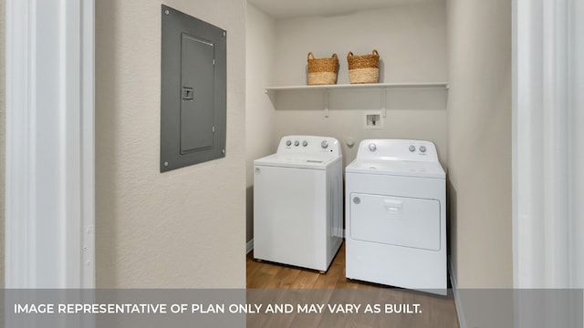 clothes washing area with electric panel, washer and dryer, and wood-type flooring