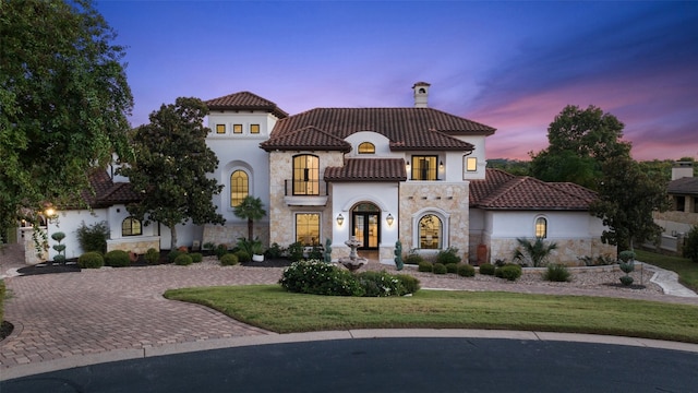 mediterranean / spanish-style house featuring french doors, a lawn, and a balcony