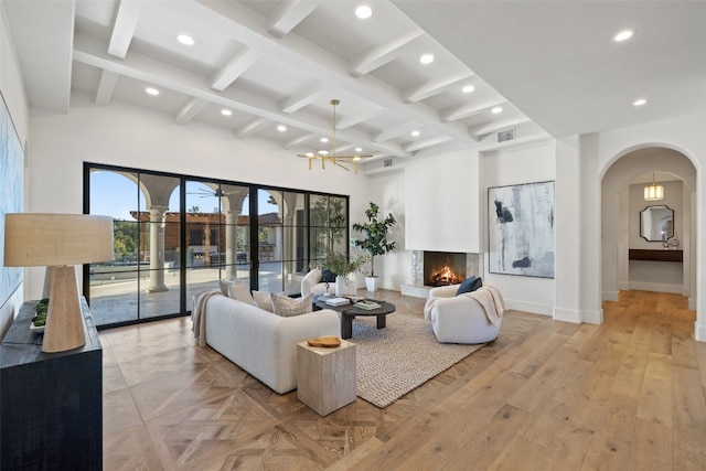 living room with beam ceiling, coffered ceiling, an inviting chandelier, and light wood-type flooring