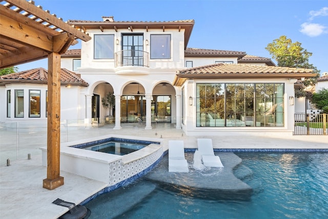 rear view of property with a patio, a pool with hot tub, and a balcony