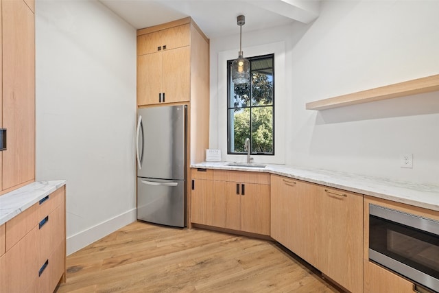 kitchen with light stone countertops, light brown cabinetry, light hardwood / wood-style flooring, pendant lighting, and stainless steel appliances