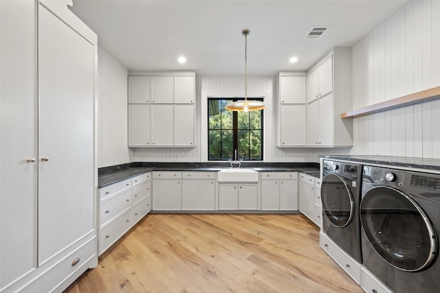 clothes washing area with sink, independent washer and dryer, cabinets, and light hardwood / wood-style flooring