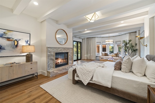 bedroom featuring beam ceiling, hardwood / wood-style floors, and a fireplace