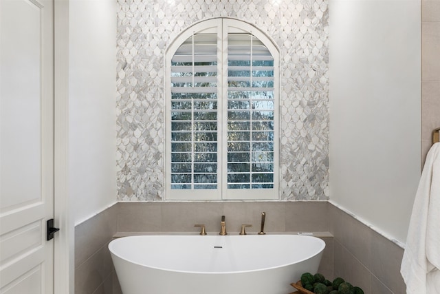 bathroom featuring a tub, tile walls, and a wealth of natural light